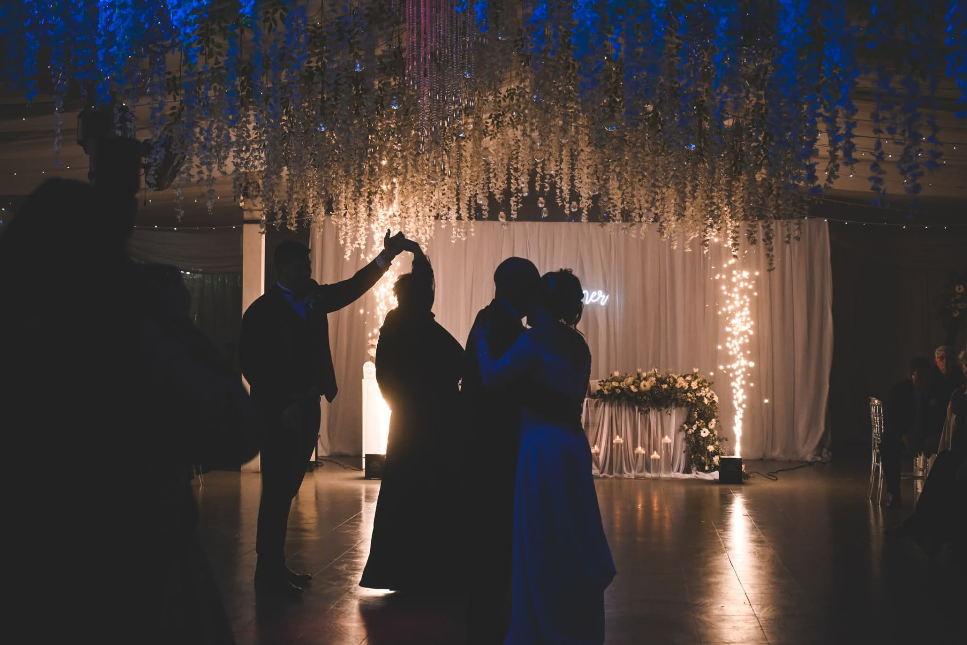 Silhouettes of wedding guests dancing in front of a tall indoor cold spark fountain at Arabest in Despatch