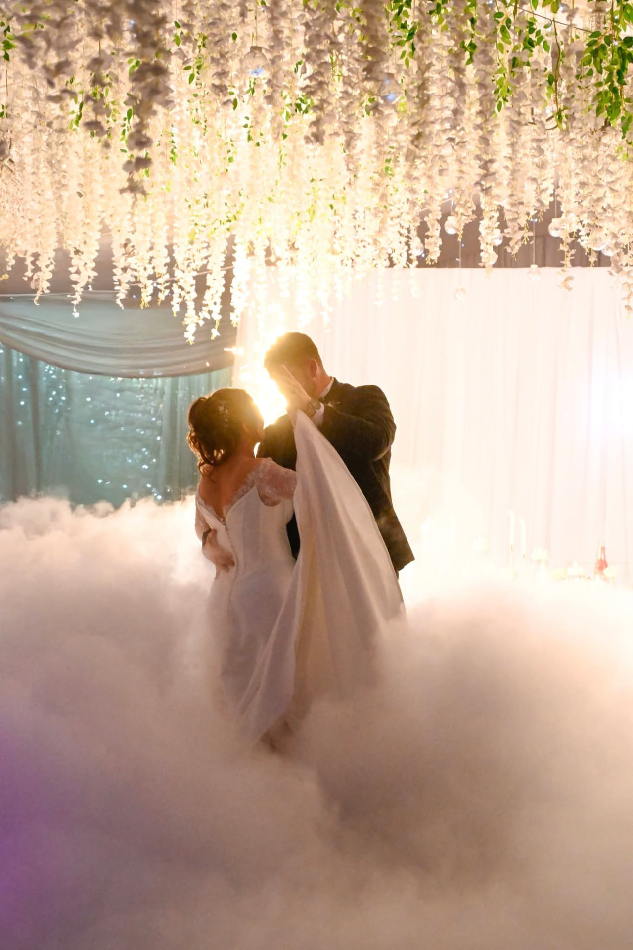 Bride's veil lifted as the couple kiss on a thick dry ice cloud with an indoor cold spark fountain behind them at Arabest, Despatch
